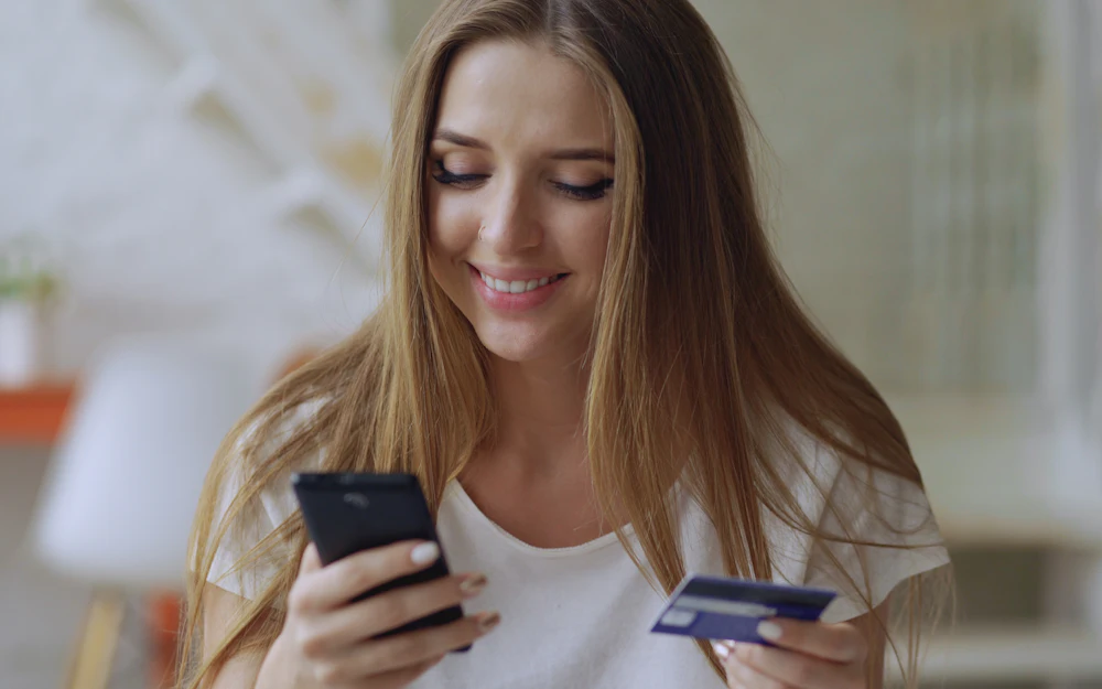 A person using a smartphone and payment card for online banking